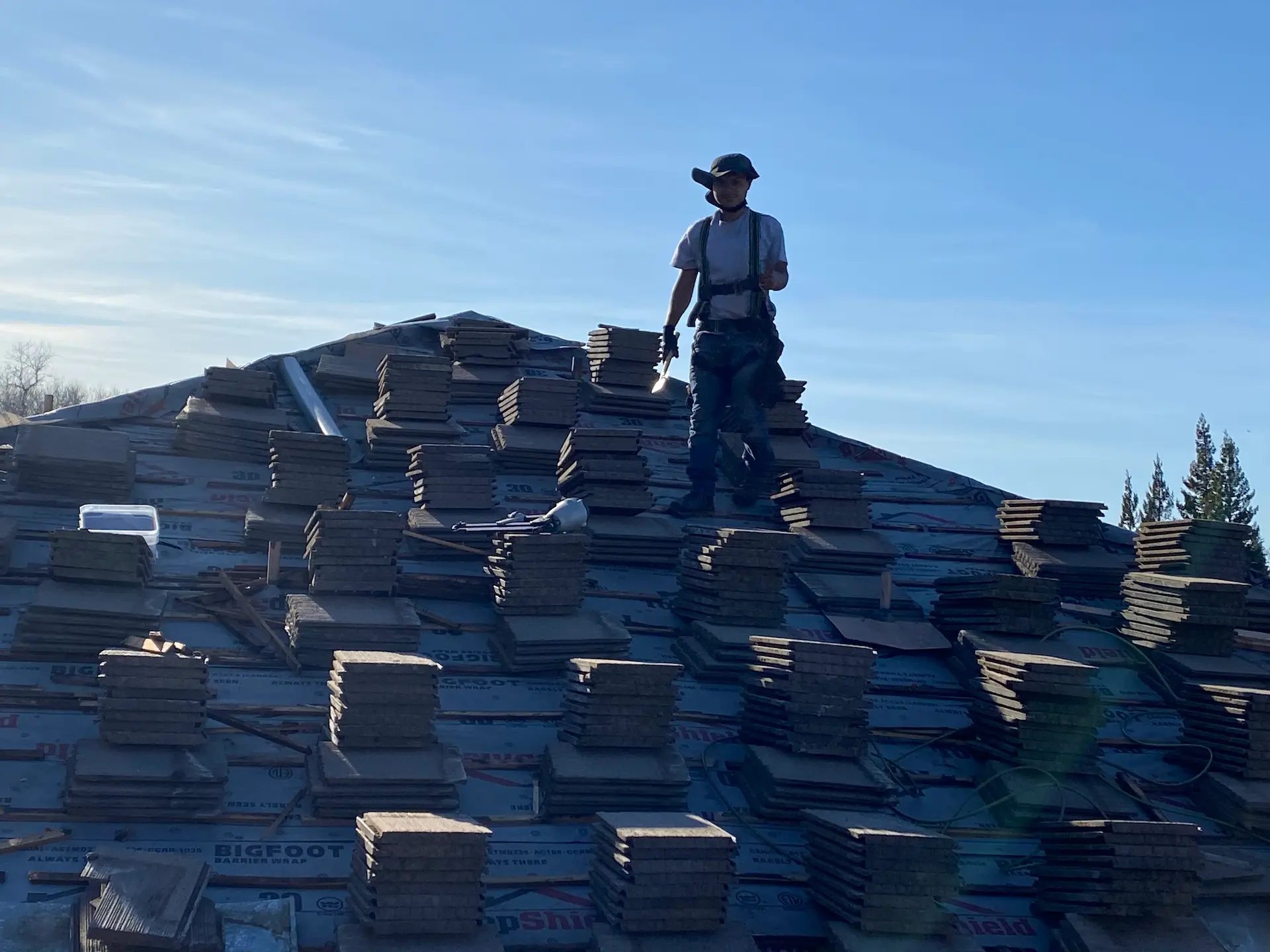 Worker on shingle roof peak